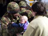 A British NATO peacekeeper hands over a Serb baby to its mother after getting out of an ambulance  in the northern Kosovo city of Kosovska Mitrovica, Sunday, March 21, 2004