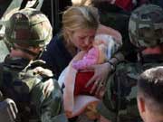 Vojnici KFOR-a iseljavaju Srpkinju sa bebom pred naletom razularenih albanskih grupa koje pale srpske kuce (foto AP)
